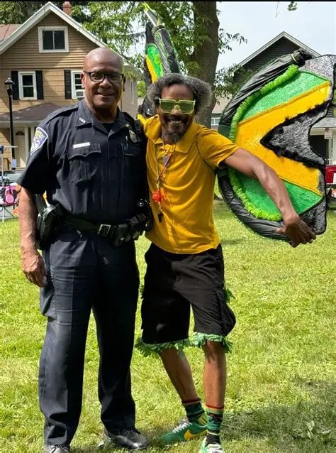 Moses Robinson in uniform with a dancer in a Jamaican-flag costume at a Caribbean festival