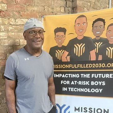 Moses Robinson beside a Mission Fulfilled 2030 banner, a program for at-risk boys in technology