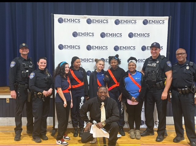 Officers and students in safety patrol sashes at a school event